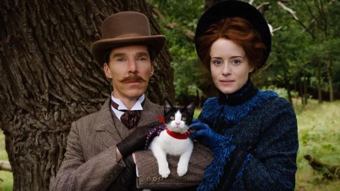 A scene from The Electrical Life of Louis Wain with Benedict Cumberbatch (Wain) looking to camera holding a cat next to his wife Emily (Claire Foy)   