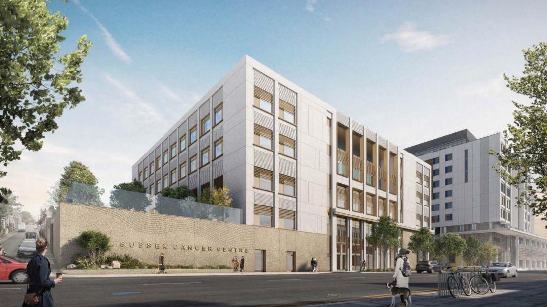 An artist's impression of the new cancer centre, a five storey building in white with a concrete wall to the side which has a glass balcony above it and the tops of trees visible. The site opens out on to a road and another taller building is seen behind it.