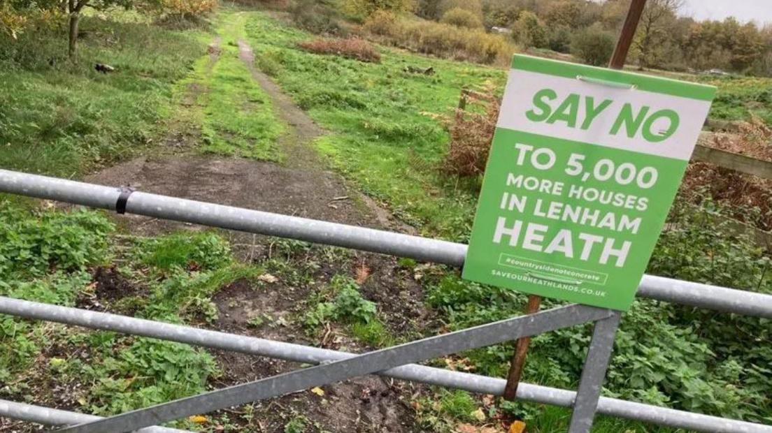 a "Say No" sign on a gate into a field 