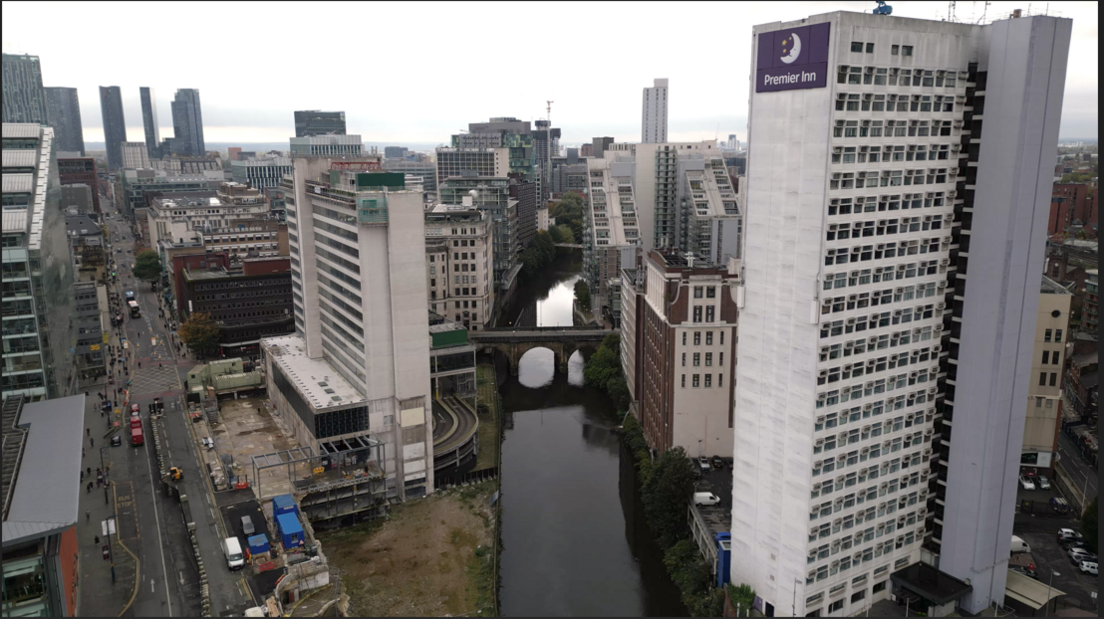 A birdseye view of the city centre as it is now, with grey high rise buildings and a bridge over a canal.