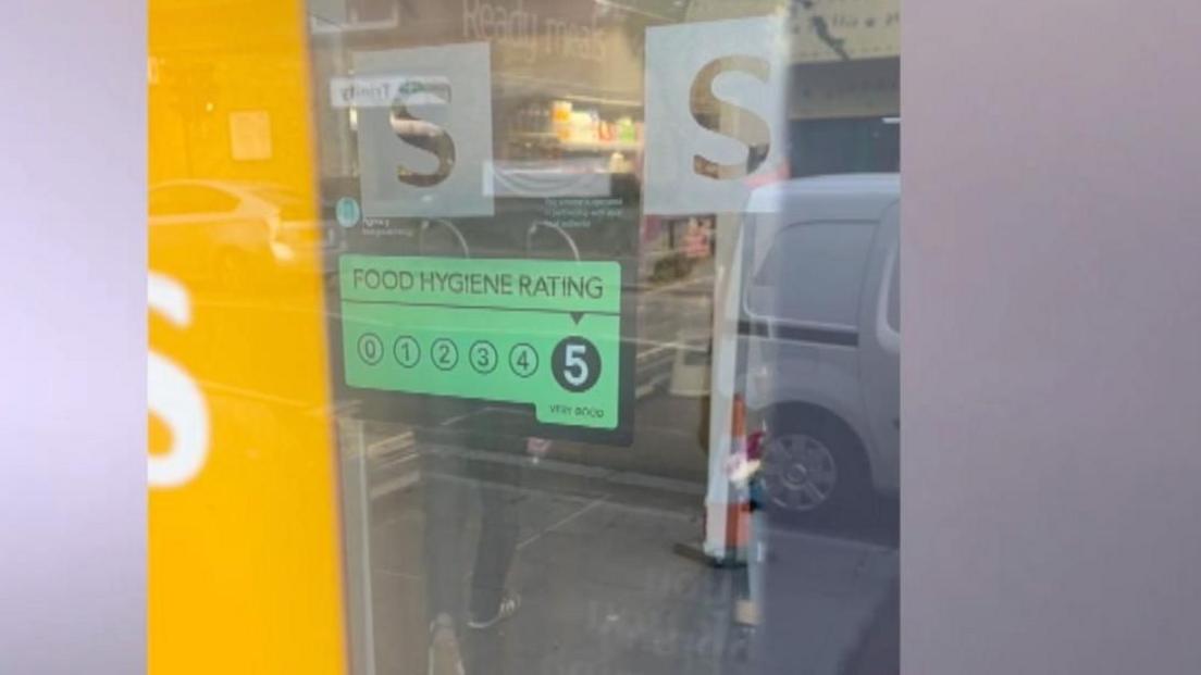 An orange and black sign on the door to a Sainsbury's Local store in Leyton filmed by the BBC as part of the investigation showing a five rating which was proved later to be incorrect, the real rating was a zero