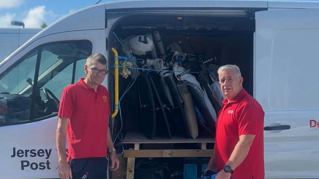 Alan and Toby stood in front of the Jersey Post van door. It is filled with equipment and Alan is putting a bag into it.