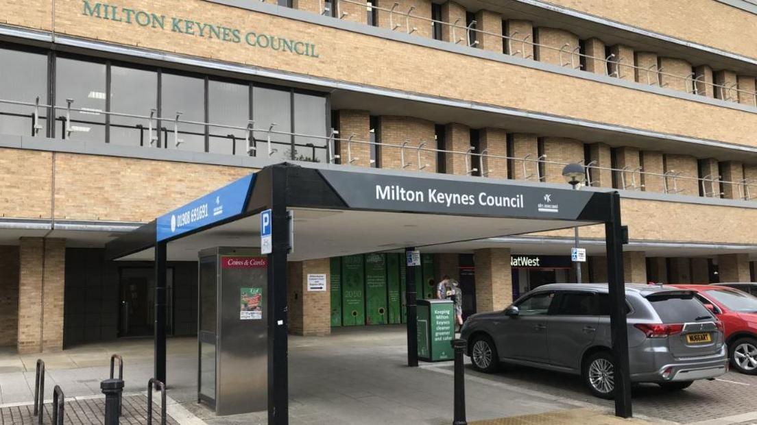 Milton Keynes Council offices. A modern brick-built block with parking spaces in front and an awning over the entrance.