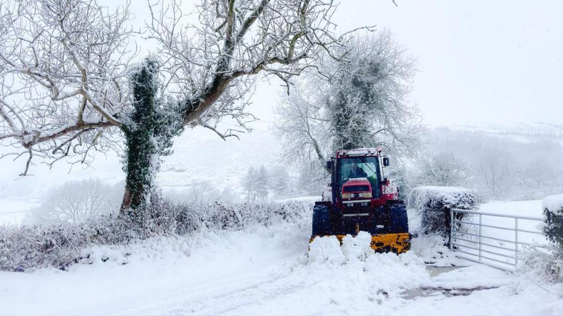 Tractor clearing snow in field