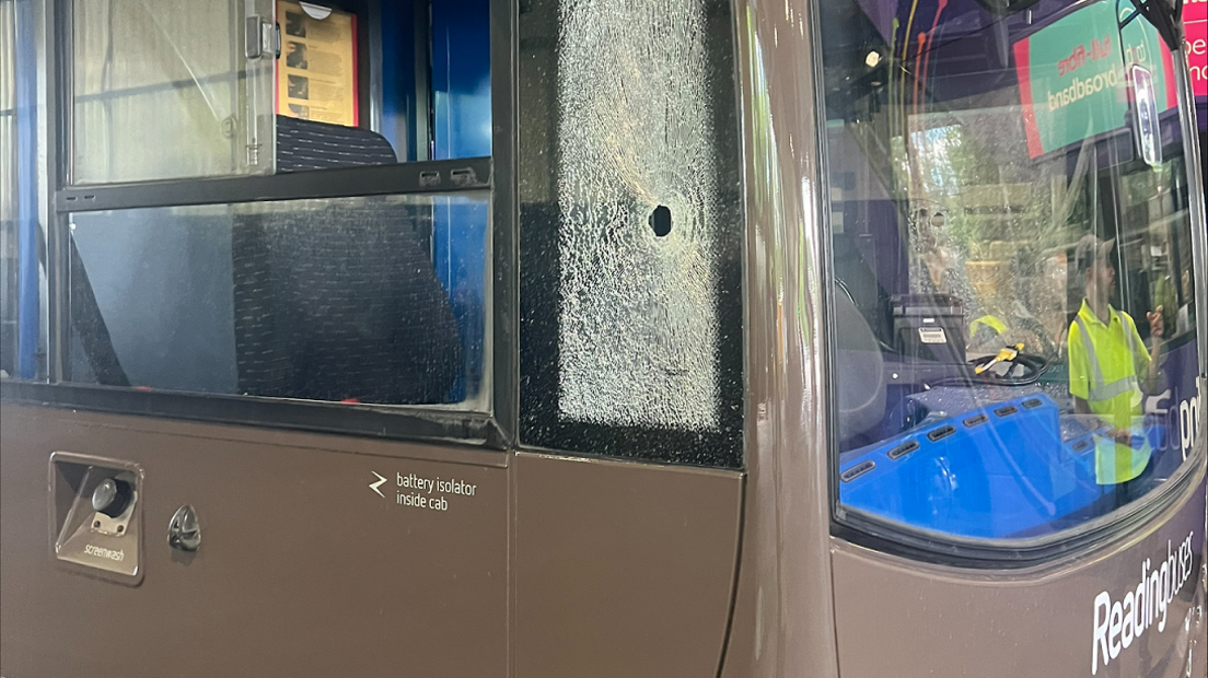 The front of a Reading Bus with the window next to its cockpit shattered, with a noticeable hole (about the size of a nut) 