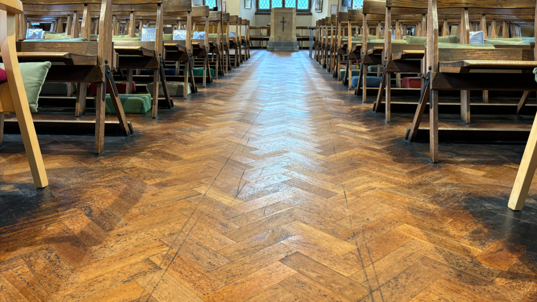 A church aisle with chairs either side, and black tyre marks etched into the wooden floor