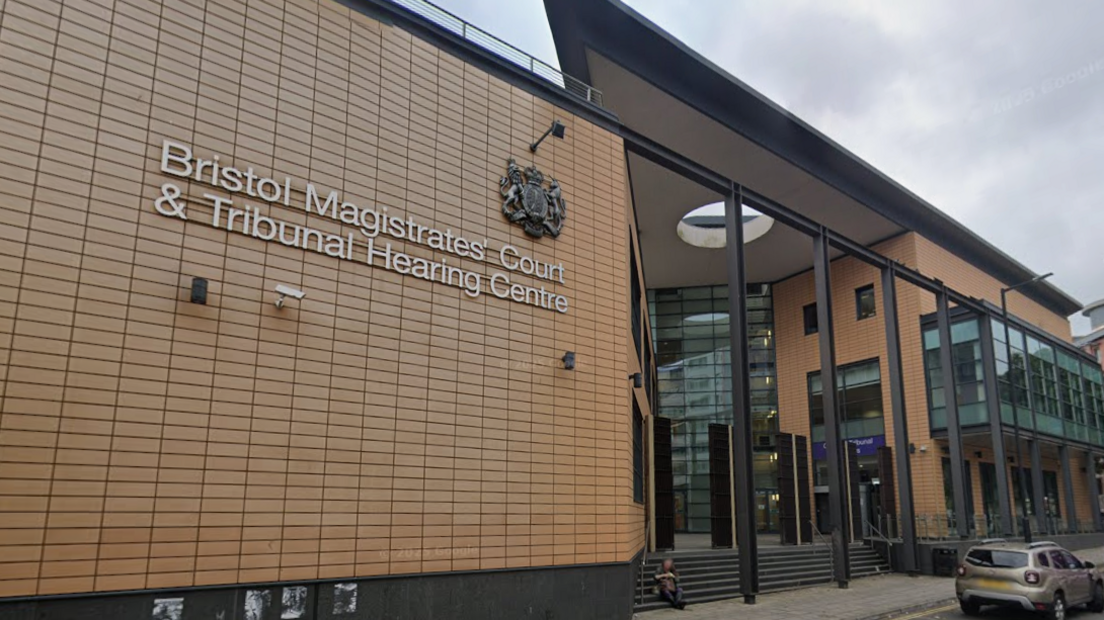 The exterior entrance to Bristol Magistrate's Court, a large brown building with steps leading up to a glass column.