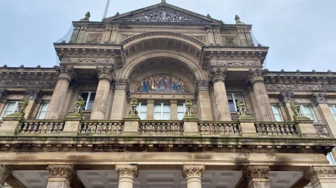A view of Birmingham City Council House, with the camera pointing upwards. An upper floor with windows is prominent on the photo.