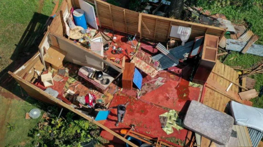 An aerial image of a home missing a roof, personal possessions lay scattered inside 