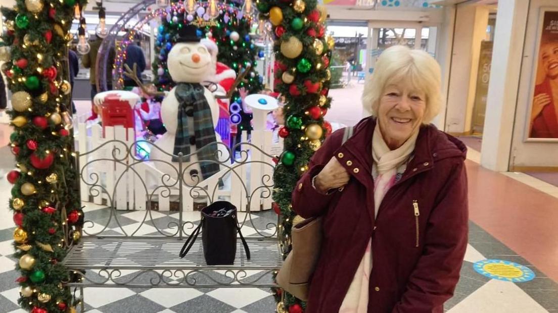 Fran Dobson in a shopping centre with Christmas decorations display behind her