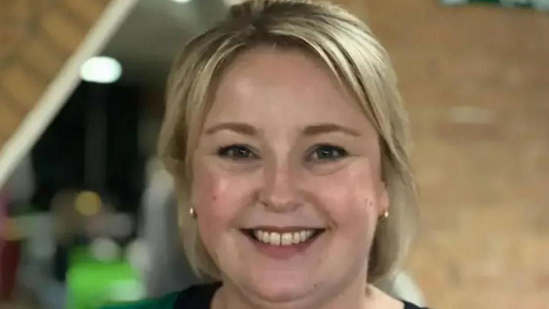 A woman with short blonde hair smiles at the camera