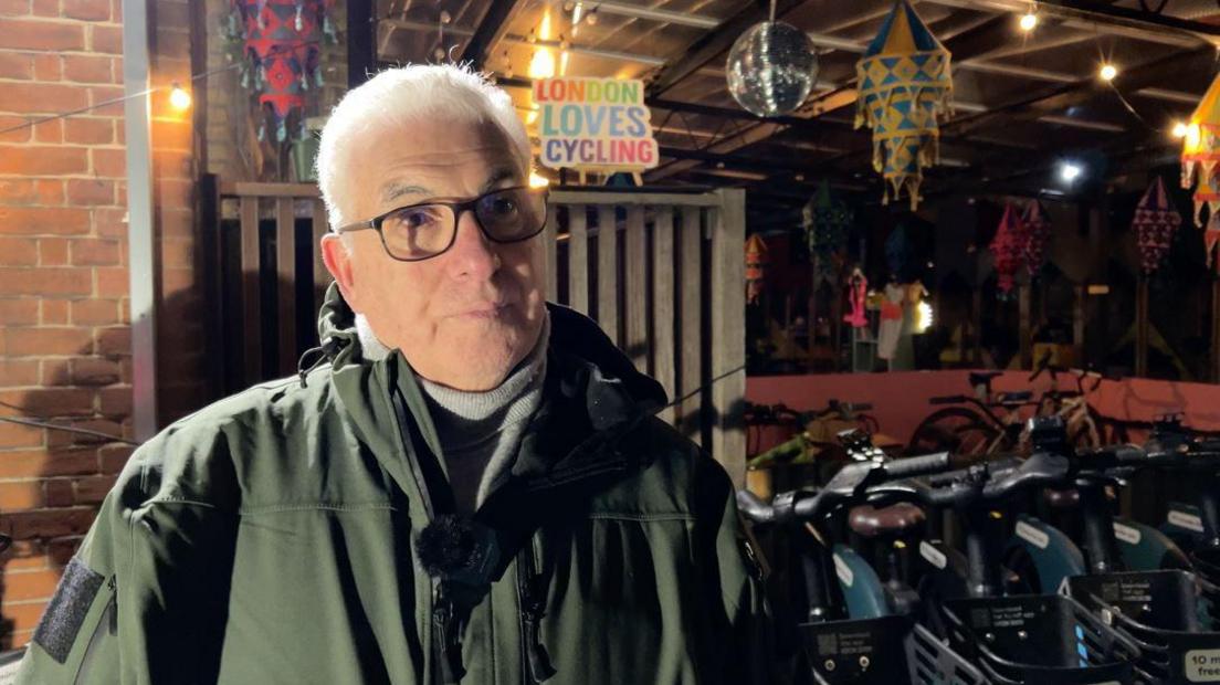 Mitch Winehouse, who has short grey hair and wears glasses with a green rainproof coat, speaks to the BBC ahead of the ride out 