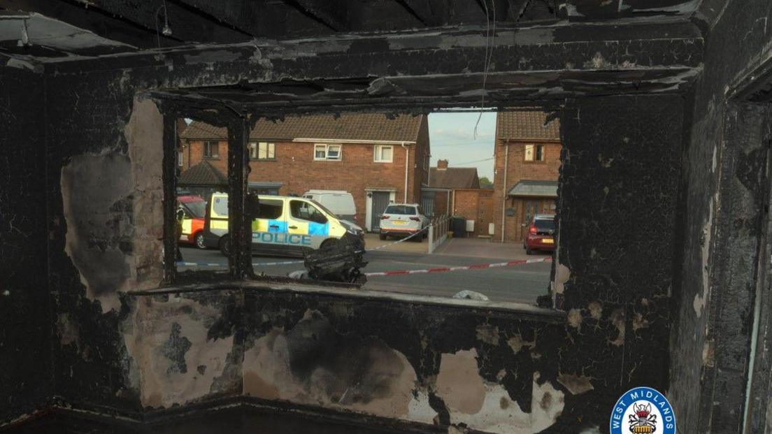 Inside of a badly burnt living room with charcoal walls 