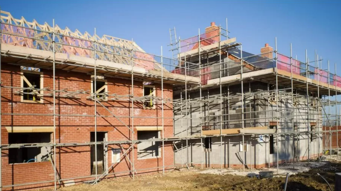 New red brick homes part way through construction, still surrounded by scaffolding poles.