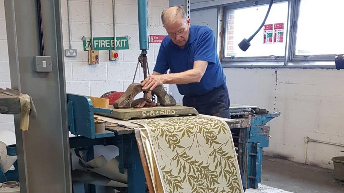 A man hand-printing wallpaper