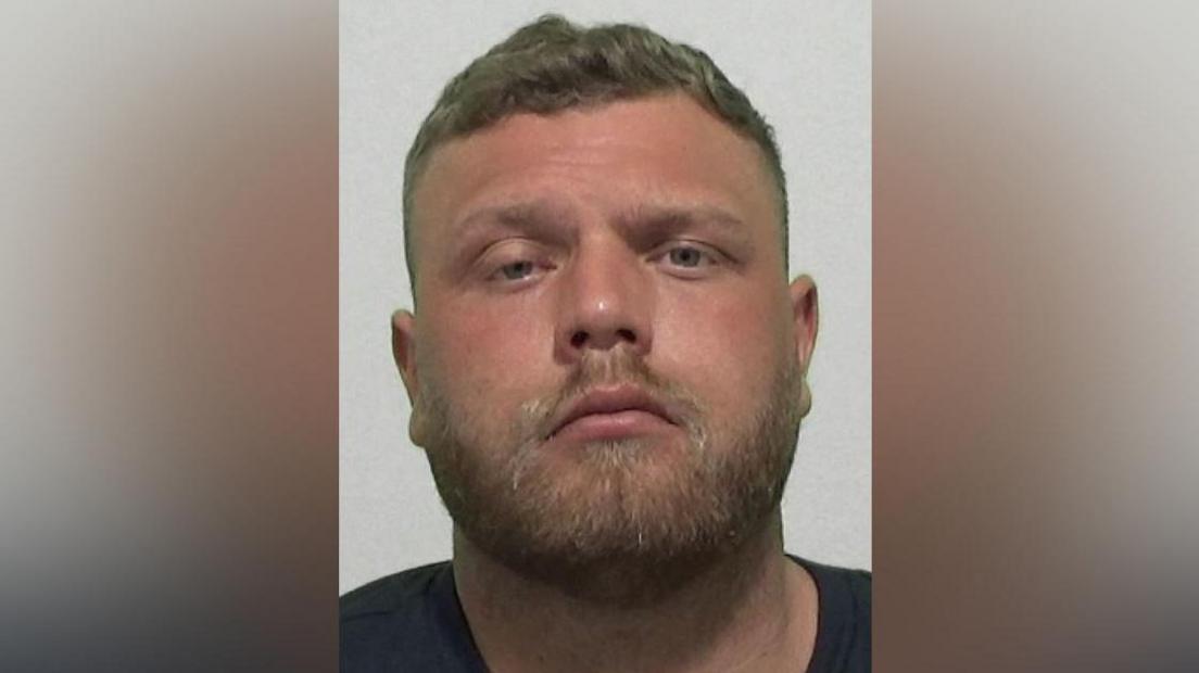 Mugshot of Maddison. He has a muscular head with a short fair beard and short dark hair.