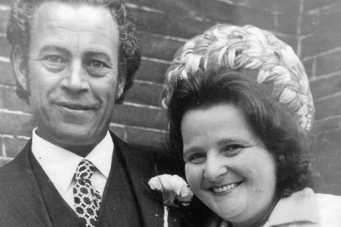 A black and white image of Mrs Gilbert with a large hat, next to her husband dressed in a dark suit and tie