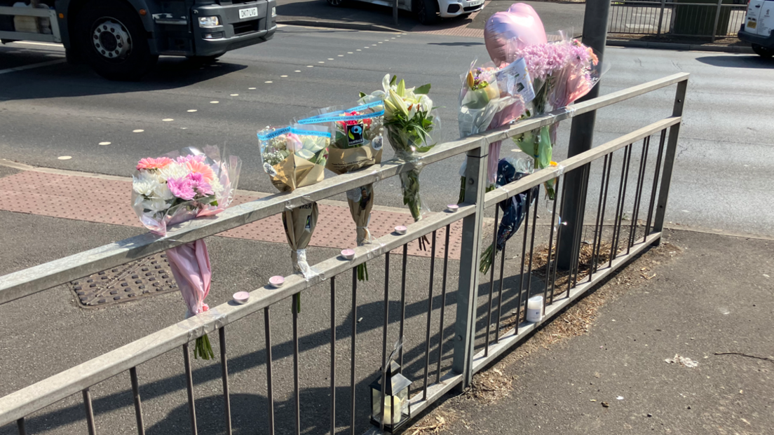 Bouquets of flowers attached to a roadside railing