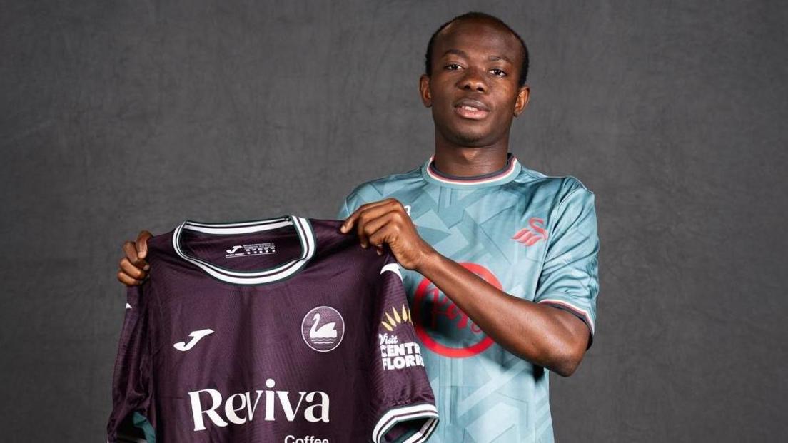 Malick Yalcouye holds up Swansea's away shirt 