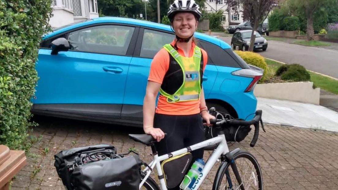 Emma Davis in cycling gear with fluorescent bib and black and white helmet about to set off for Paris