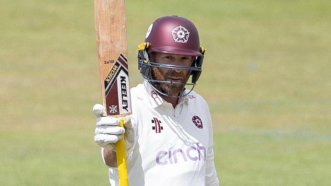Luke Procter raises his bat during an innings for Northamptonshire