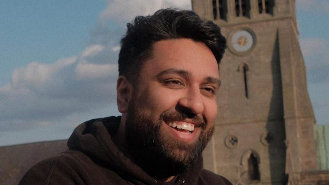 Nico Singh is standing outside smiling.