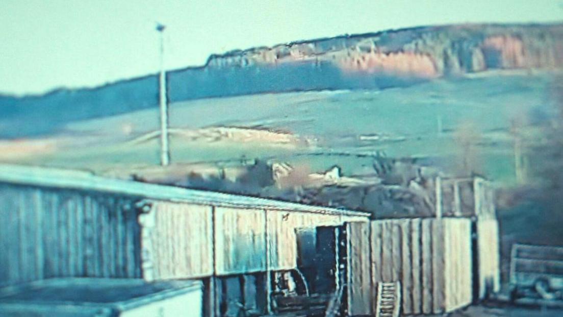 CCTV of a farm and fields with a white horse in one of the fields 