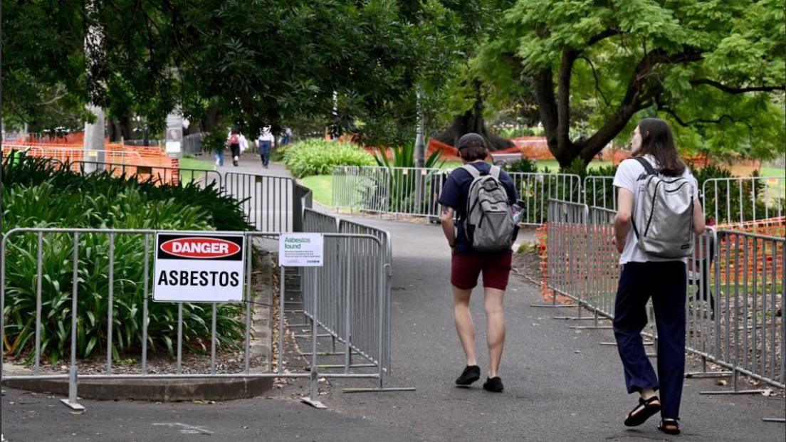 People walking by an asbestos sign