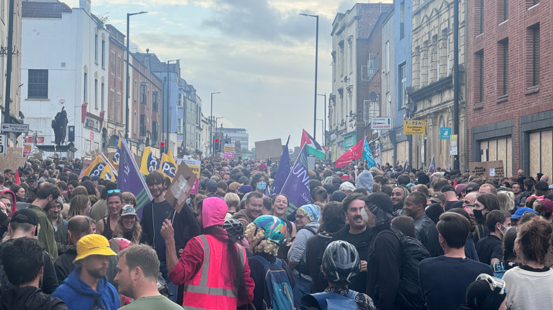 A crowd of people standing together, some with flags