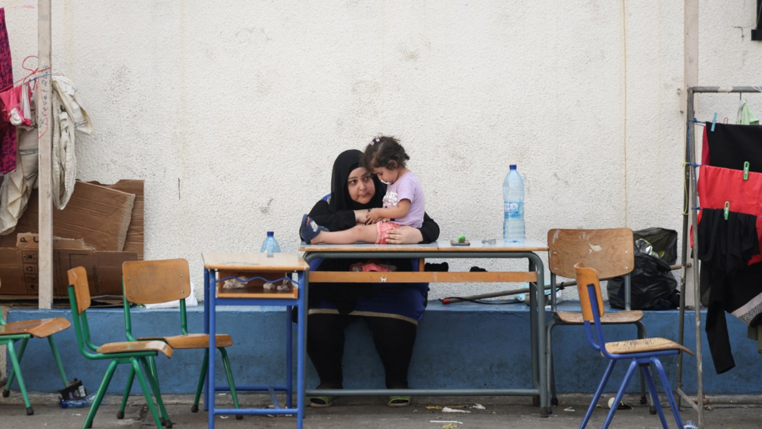 A woman talks with a child in a school turned into a temporary shelter for displaced people in Lebanon