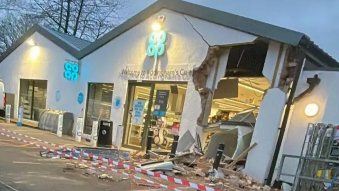 An exterior view of a Co-op supermarket early in the morning with part of the wall caved in and debris om the ground outside