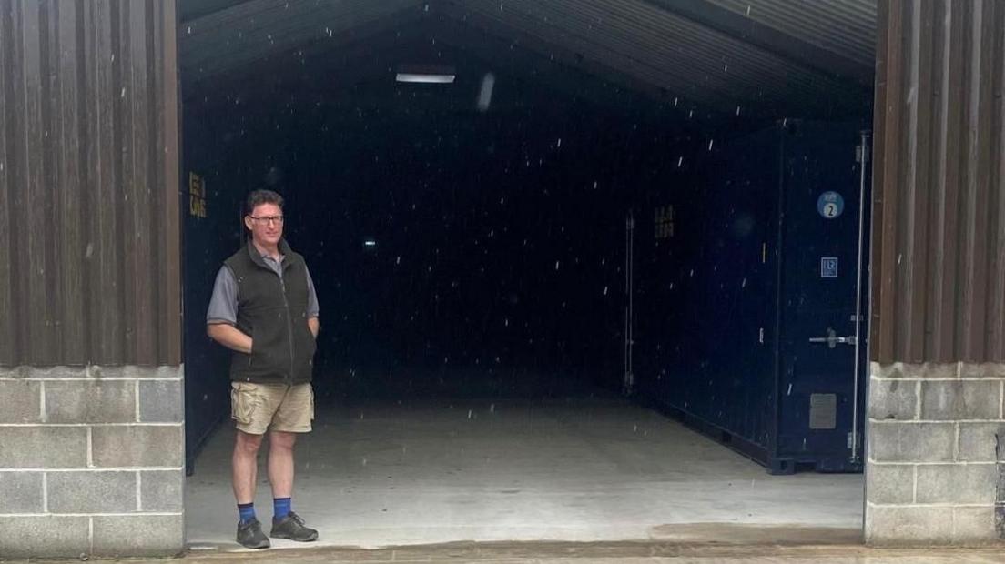 Adam Stratton has his hands in his pockets as he stands in the doorway of a storage unit