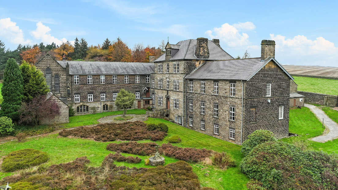 The building is set in 18 acres of green land. Bushes and trees are either side and there is a path leading to the back. In the distance behind is open land.