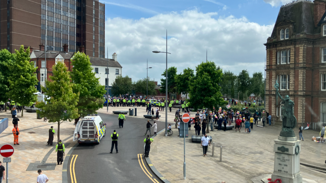 Police officers stand between two groups of people in Hanley, Stoke-on-Trent