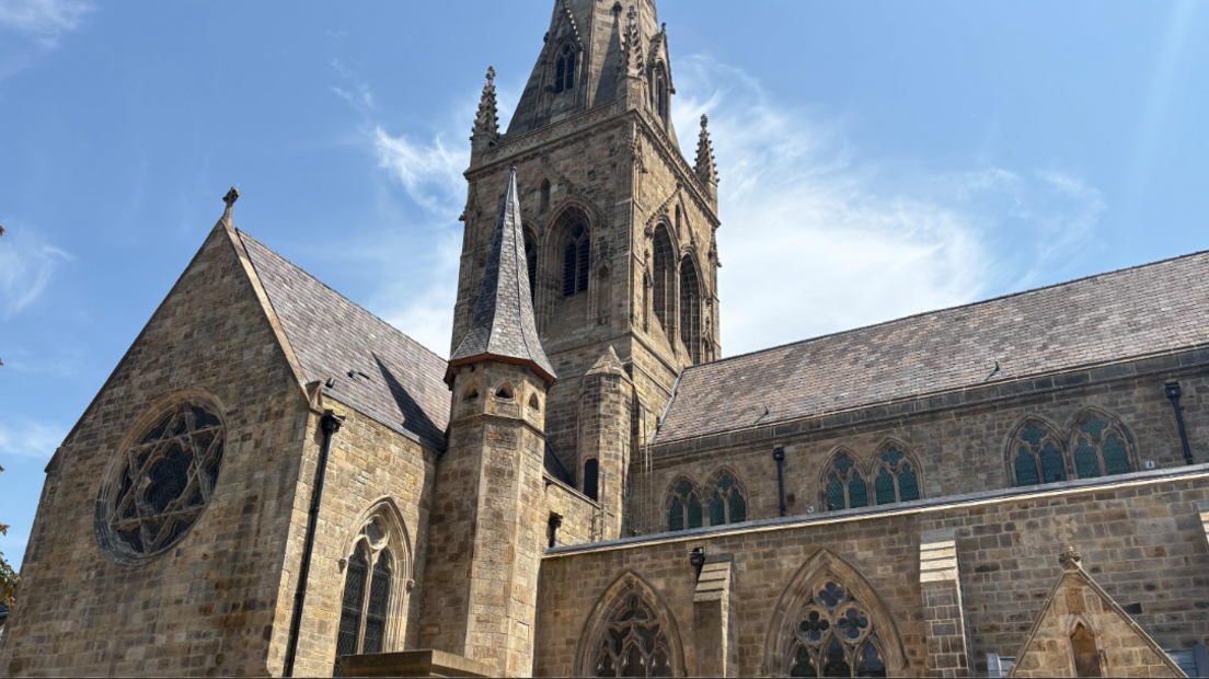Exterior Salford Cathedral with blue sky and clouds in the background.