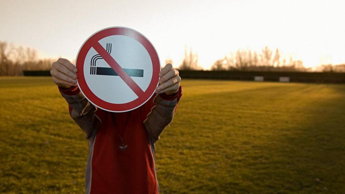 boy holding no smoking sign. 