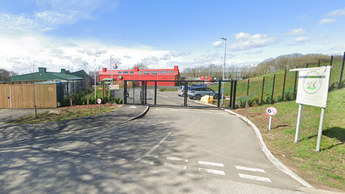 The school gates in front of a bright red school building