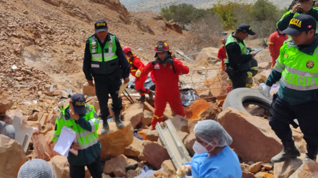 Emergency workers clamber over boulders at the bottom of the ravine.
