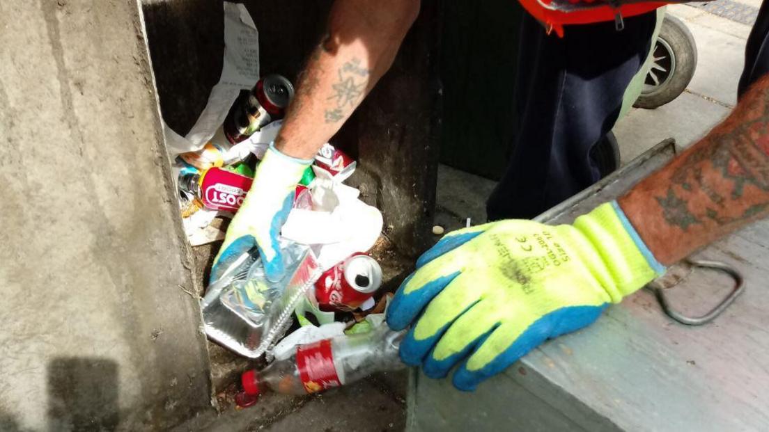 gloved hands picking up litter 