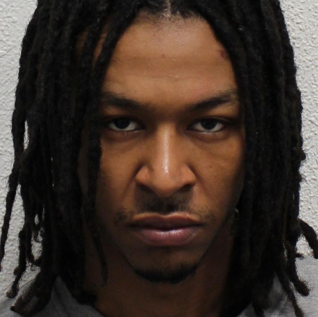 Police mugshot of Nathan Tokosi, wearing a grey sweatshirt and looking at the camera with a grumpy face.