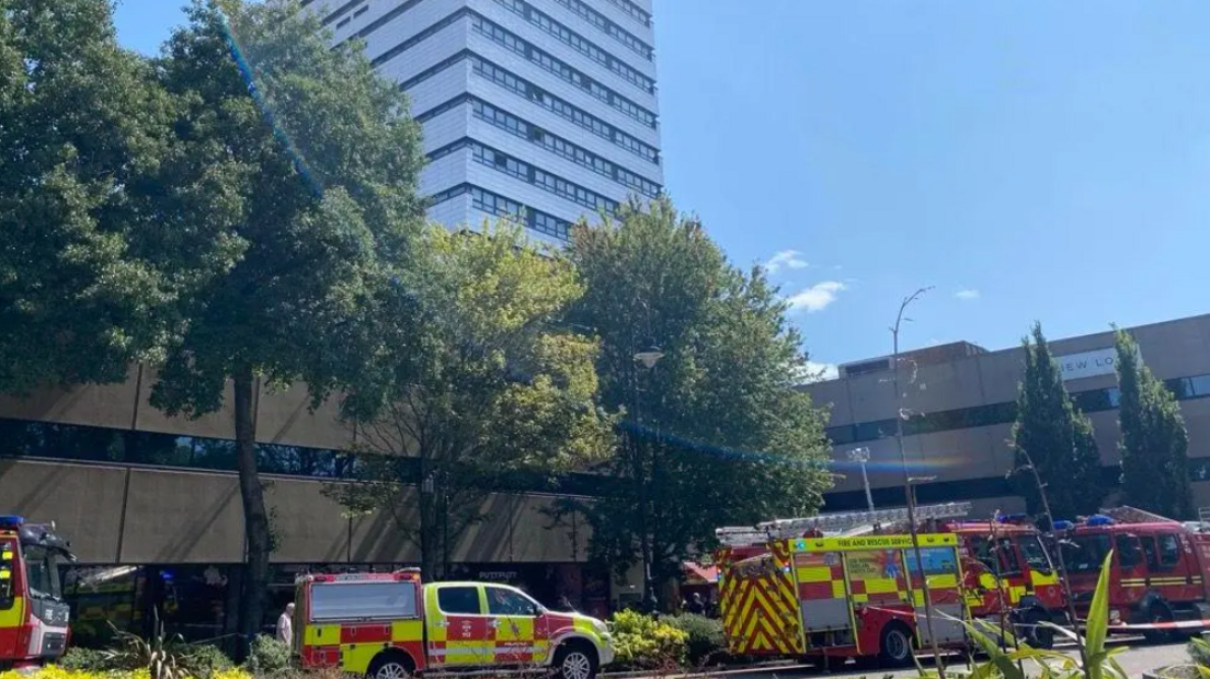 A number of fire trucks and cars parked outside the front of a tower block
