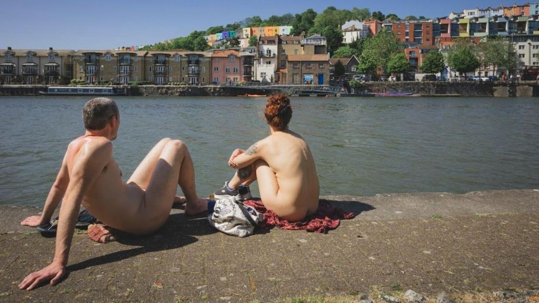 A man and a woman sitting naked by Bristol Harbourside