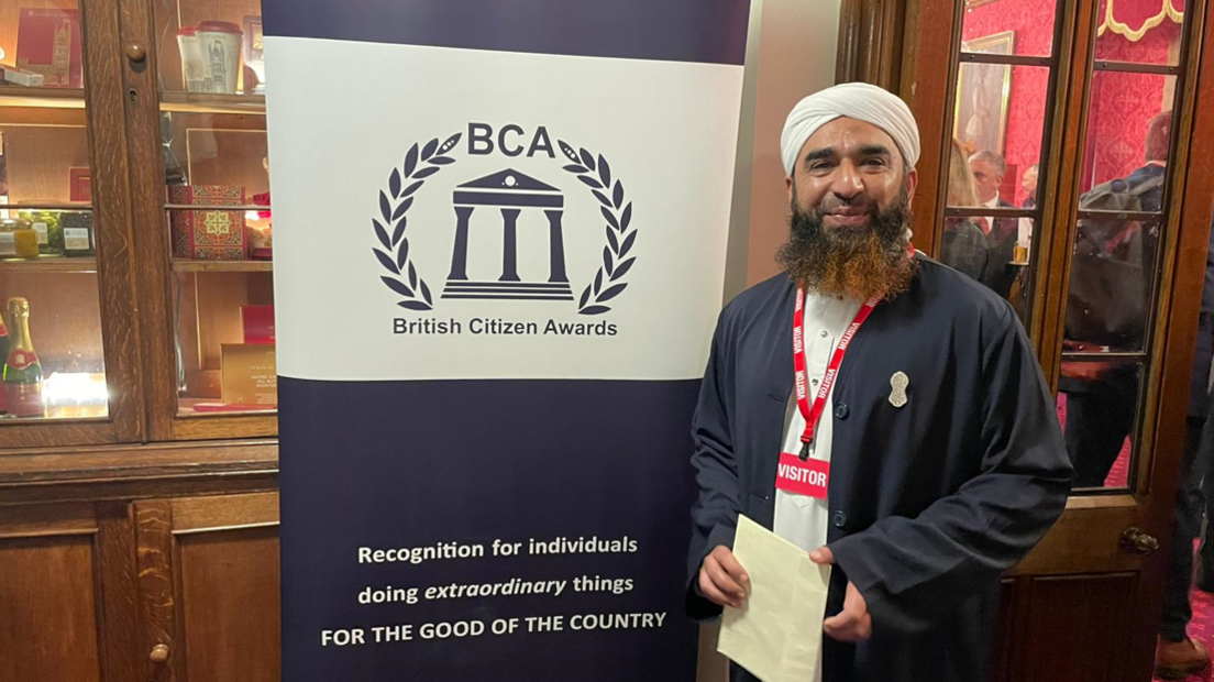 Syed Muhammad Faisal Sami stood by a British Citizen Awards banner