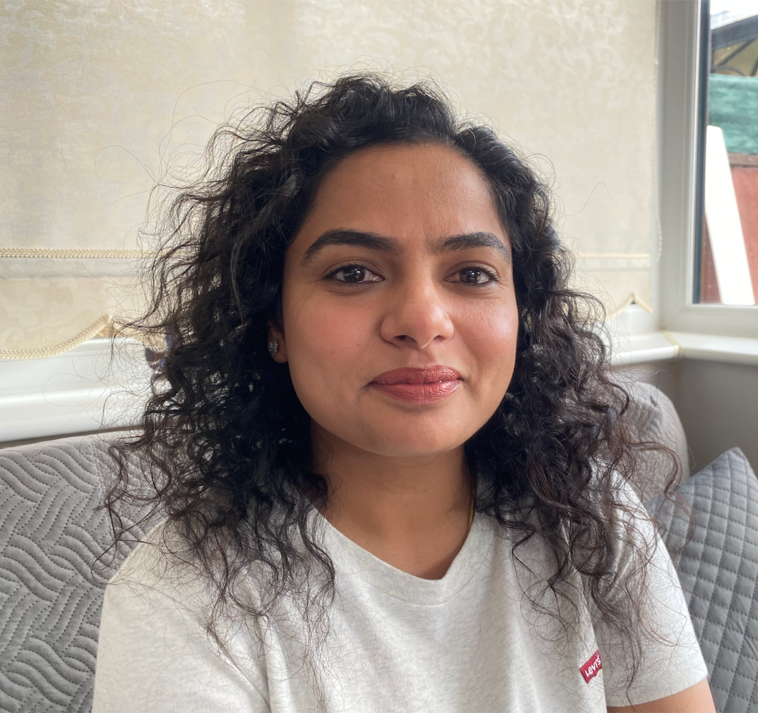 Mrs Raman Kaur is a young woman who is wearing a grey t-shirt.  She has black curly hair. 