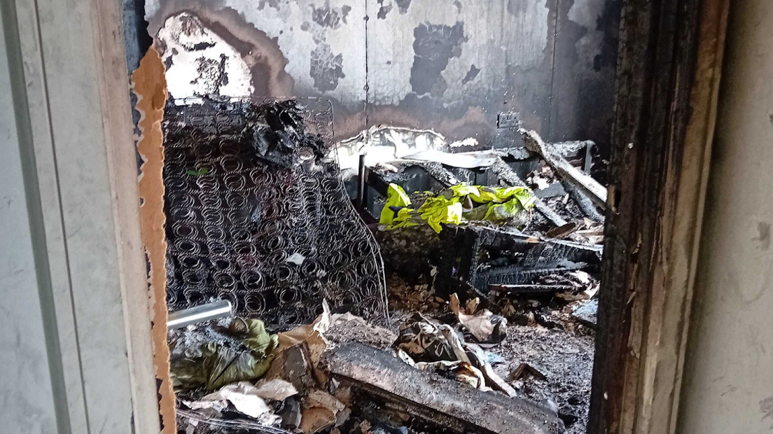 The wreckage of the fire in a room in Nabeel Ahmad's flat, including a burned out bed, from which the exposed metal of a mattress is shown. 