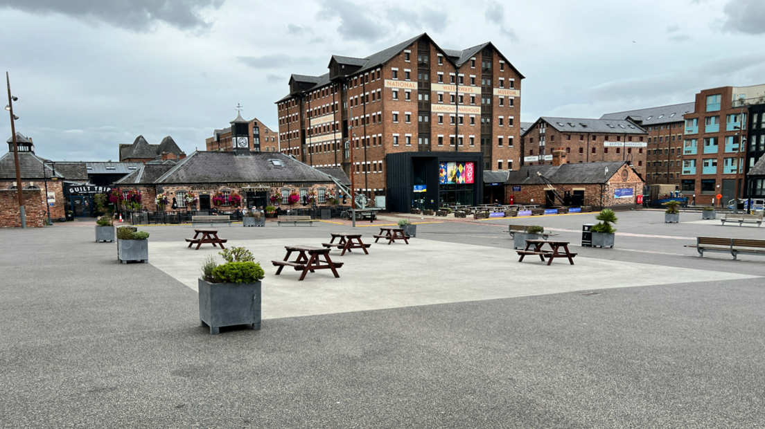 A deserted city centre with benches, planters and bricked buildings in the background