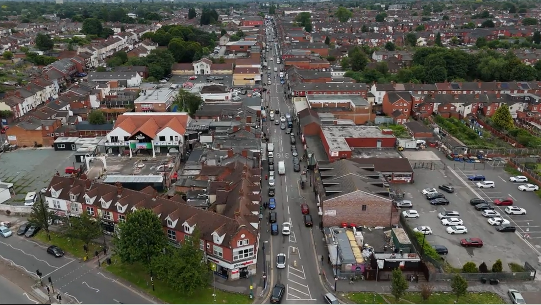 A drone shot looking at a long busy road with roads coming off it either side