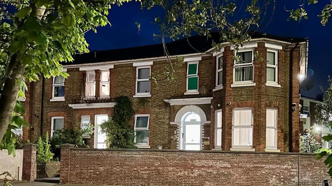 Fleming House, a building converted from a large Victorian house or several houses, pictured as the sky darkens with the windows brightly lit