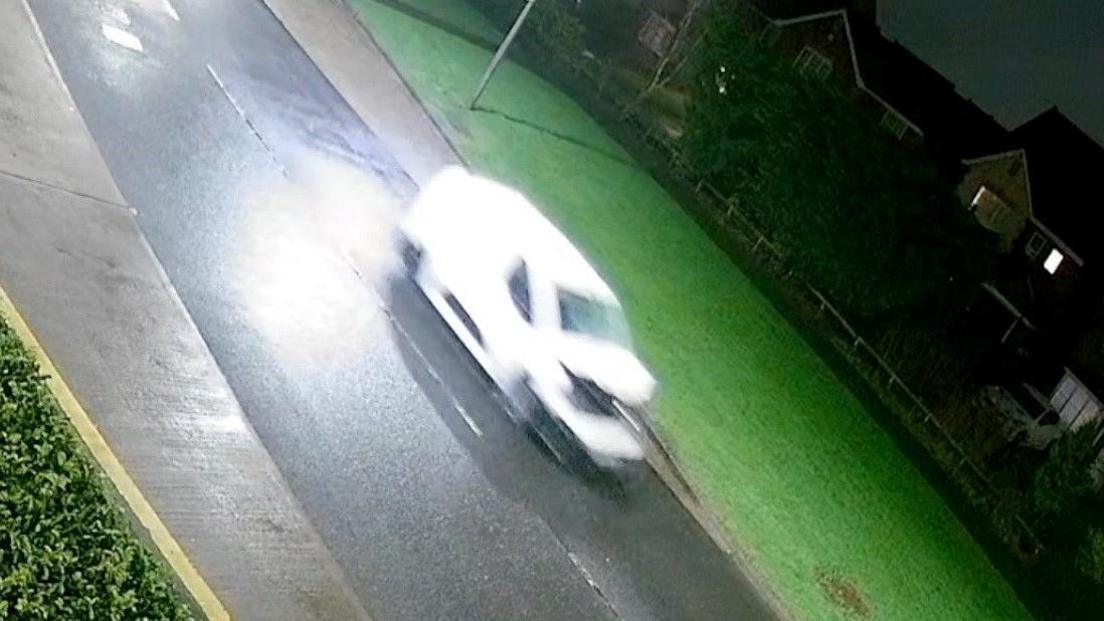 A CCTV still of a blurry white van with a crumpled bonnet and smashed windscreen