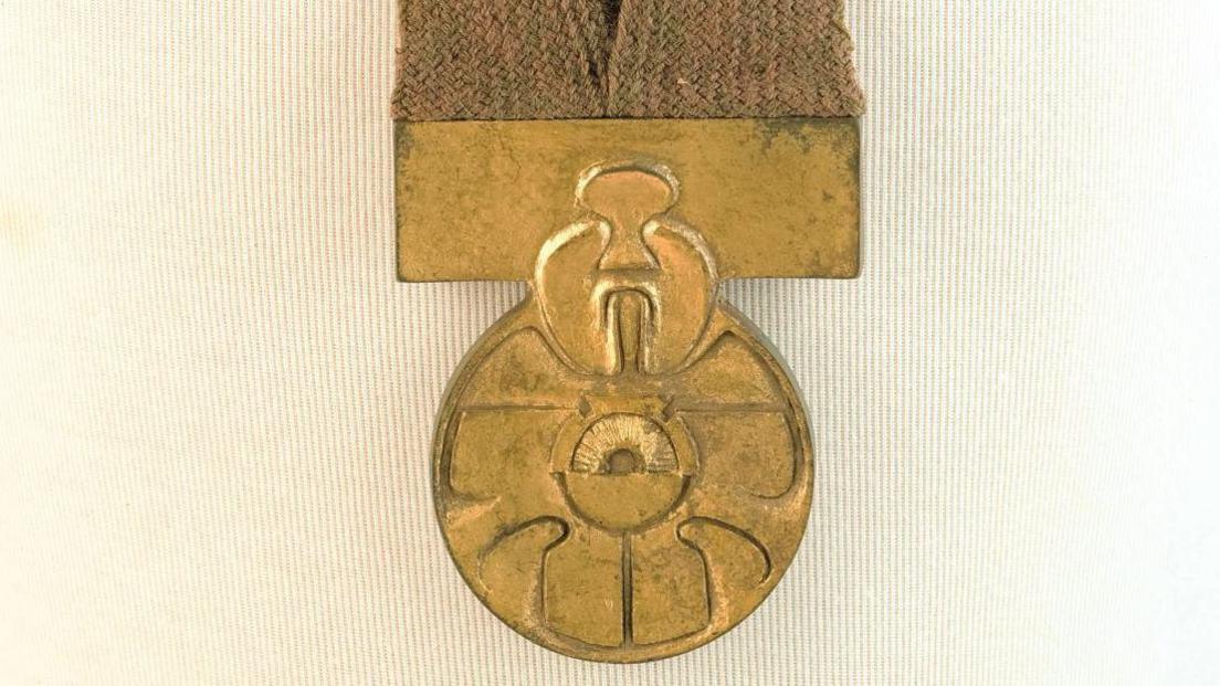 A gold medal attached to a brown fabric.